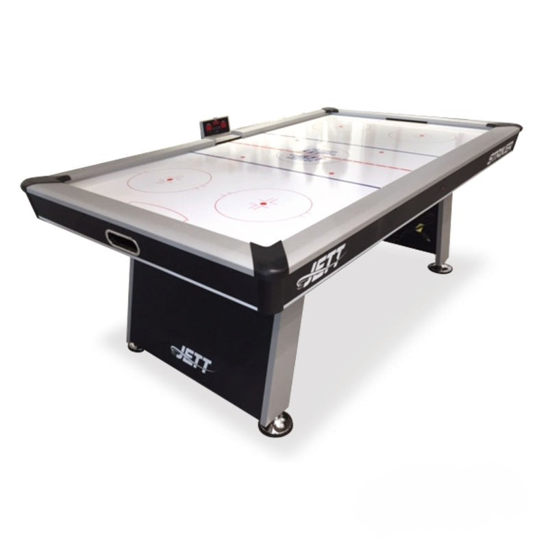 A Jet air hockey table with a black and silver frame, featuring a white play surface with red markings, shown on a white background.